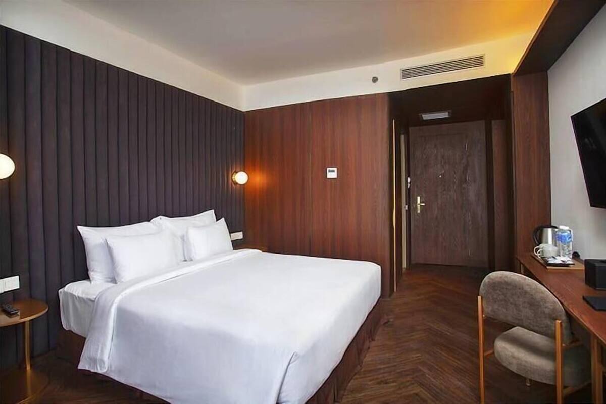 Une chambre d’hôtel avec un grand lit, un bureau, une chaise, une télévision et une porte.