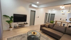 Una sala de estar moderna con un televisor de pantalla plana, un sofá, una mesa de centro y una planta en maceta.