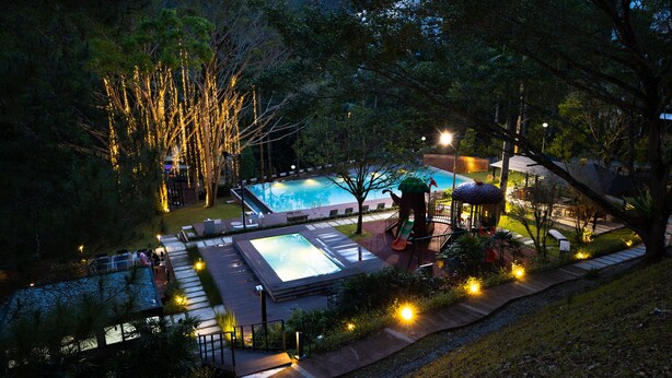 Una piscina con hidromasaje, rodeada de árboles y mobiliario de exterior.