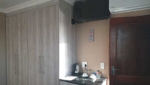Une cuisine avec des meubles de rangement en bois, un plan de travail, une bouilloire et un four à micro-ondes.