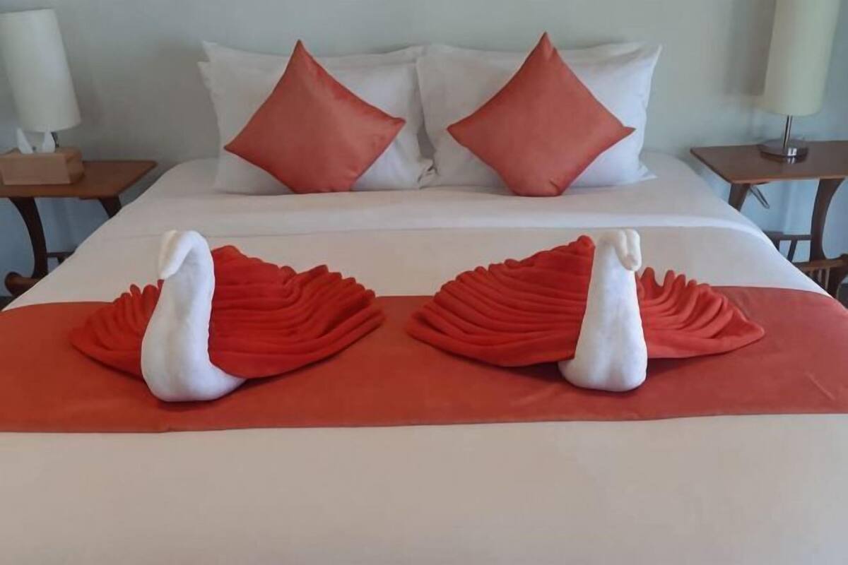 Une chambre d’hôtel avec un lit, des oreillers et deux serviettes en forme de cygne.