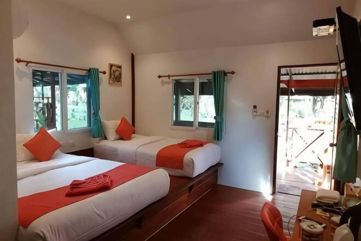 Une chambre avec trois lits, un bureau et une chaise.