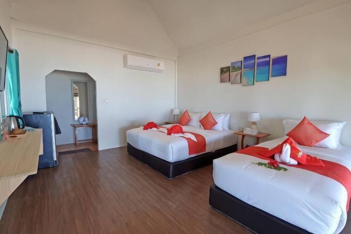 Une chambre d’hôtel avec deux lits, un bureau, une chaise, une petite table et un climatiseur fixé au mur.