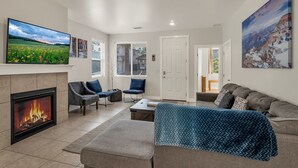 A living room with a fireplace, a large TV, and a cozy seating area. - Beautiful home! Central AC! 5 mins to Downtown! Great setting! 20% Monthly Disc! (Flagstaff)