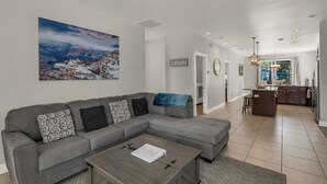 A modern living room with a sectional sofa, a coffee table, and a large landscape painting. - Beautiful home! Central AC! 5 mins to Downtown! Great setting! 20% Monthly Disc! (Flagstaff)