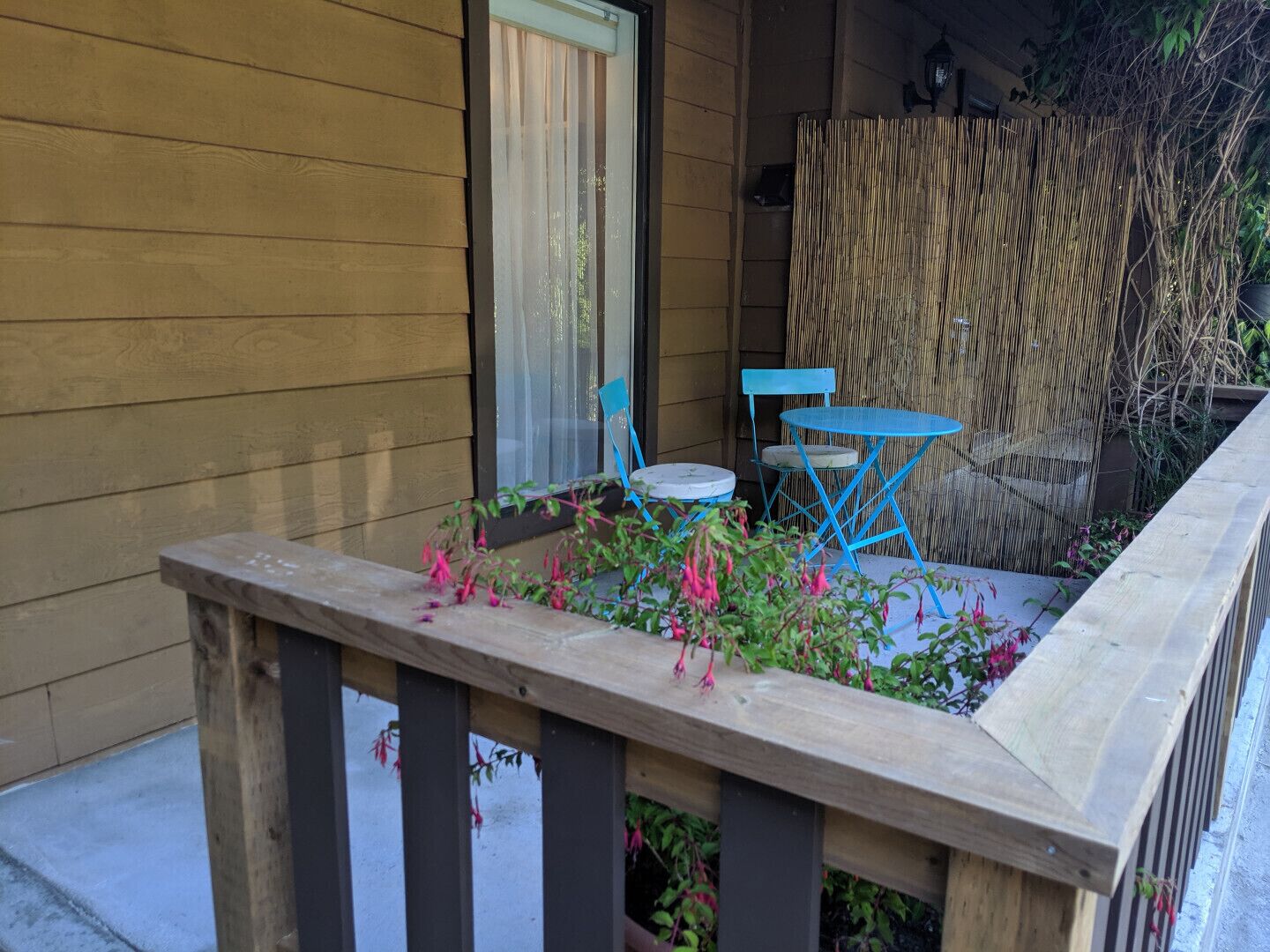 A wooden deck with a railing, a small table, and two chairs.