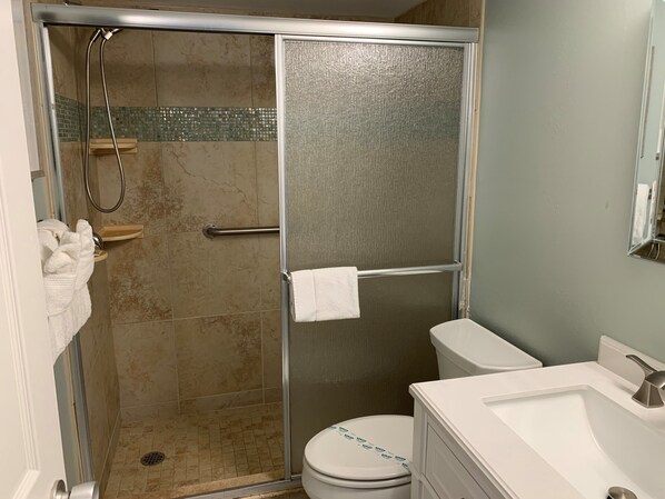 A bathroom with a glass-enclosed shower, a toilet, and a sink. - Take a peek at awesome reviews 50 feet from the sand (Longboat Key)
