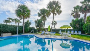 A swimming pool with lounge chairs and umbrellas, surrounded by palm trees and a hedge. - End of summer sale  Take a peek awesome reviews 50 feet from  sand (Longboat Key)