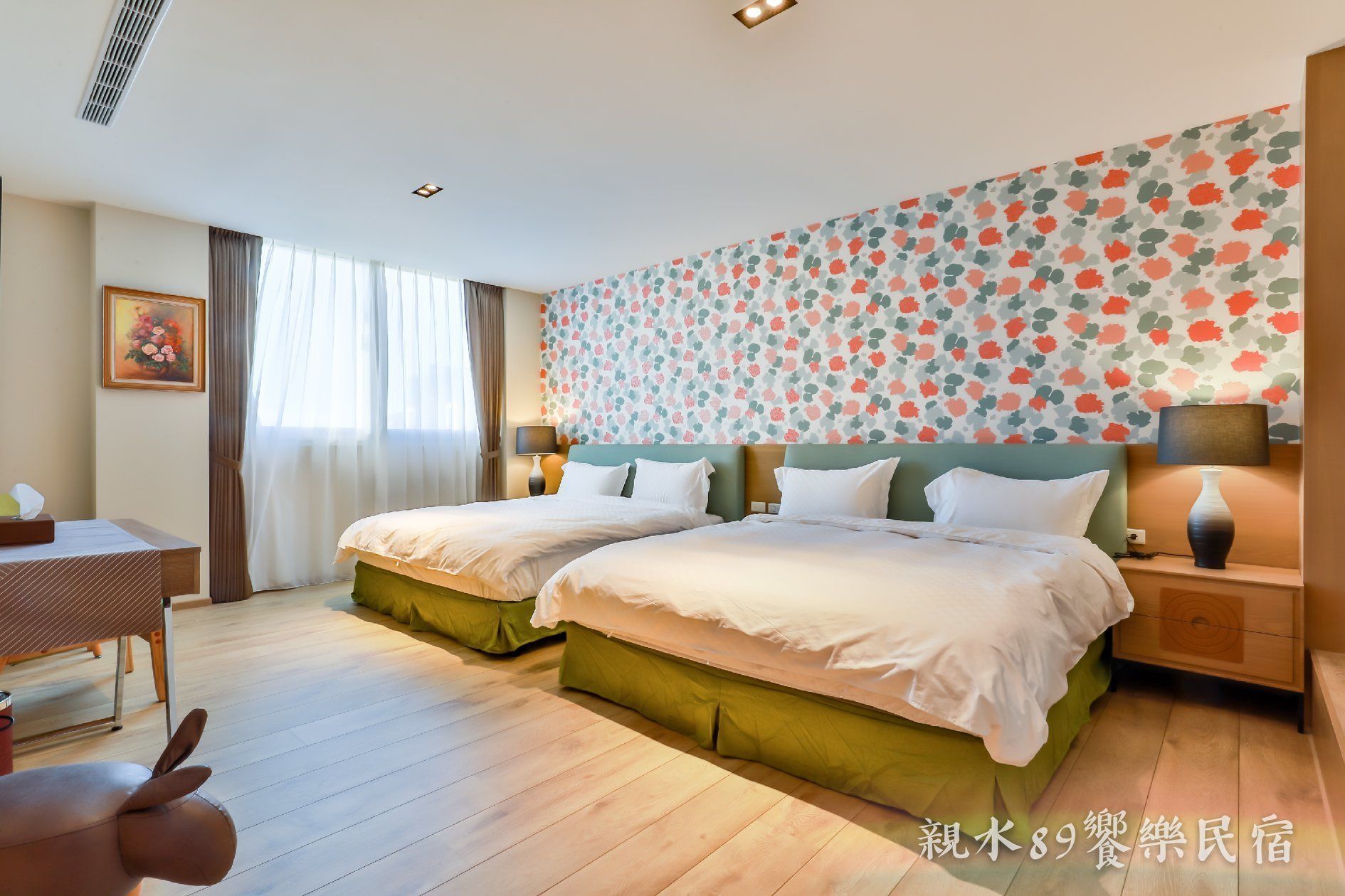 A hotel room with two beds, a desk, and a chair.