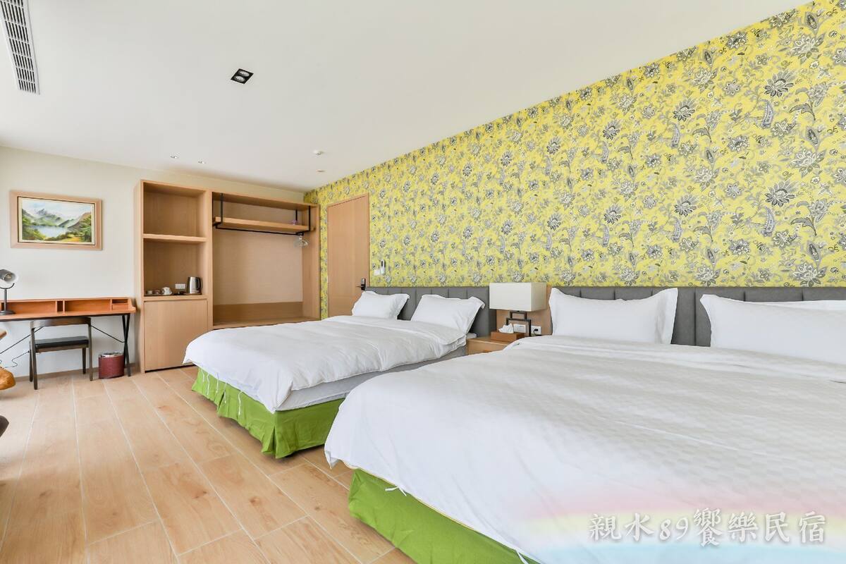 Quarto de hotel com duas camas, uma escrivaninha e um guarda-roupa.