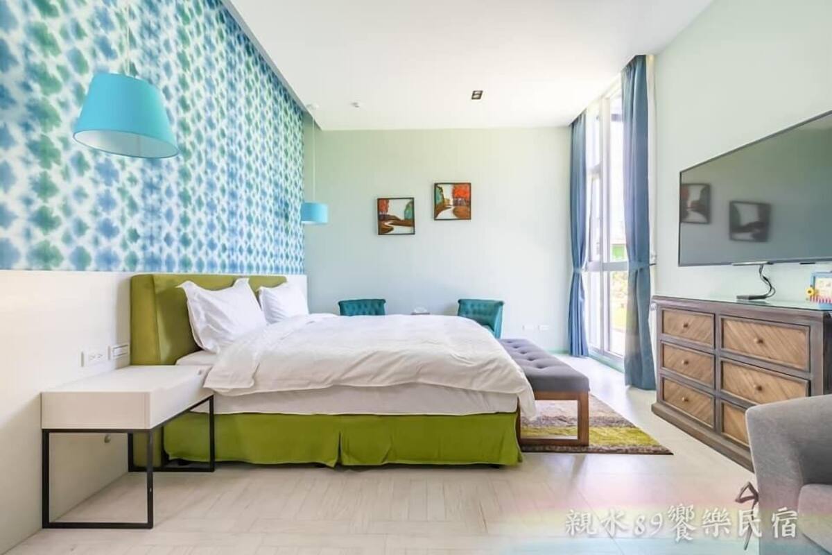 Quarto moderno com cama, mesa de cabeceira e televisão.