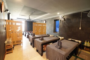 Un cuarto de spa con camillas de masaje, toallas y un ventilador de pared.
