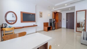A modern living room with a dining area, a kitchen with a refrigerator, and a wooden cabinet. - Kiwi Beachside Hotel & Cafe Da Nang (Da Nang)
