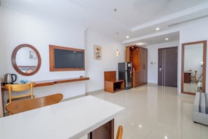 A modern living room with a dining area, a kitchen with a refrigerator, and a wooden cabinet. - Kiwi Beachside Hotel & Cafe Da Nang (Da Nang)