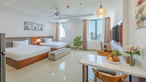 A hotel room with two beds, a dining table, a TV, and a ceiling fan. - Kiwi Beachside Hotel & Cafe Da Nang (Da Nang)