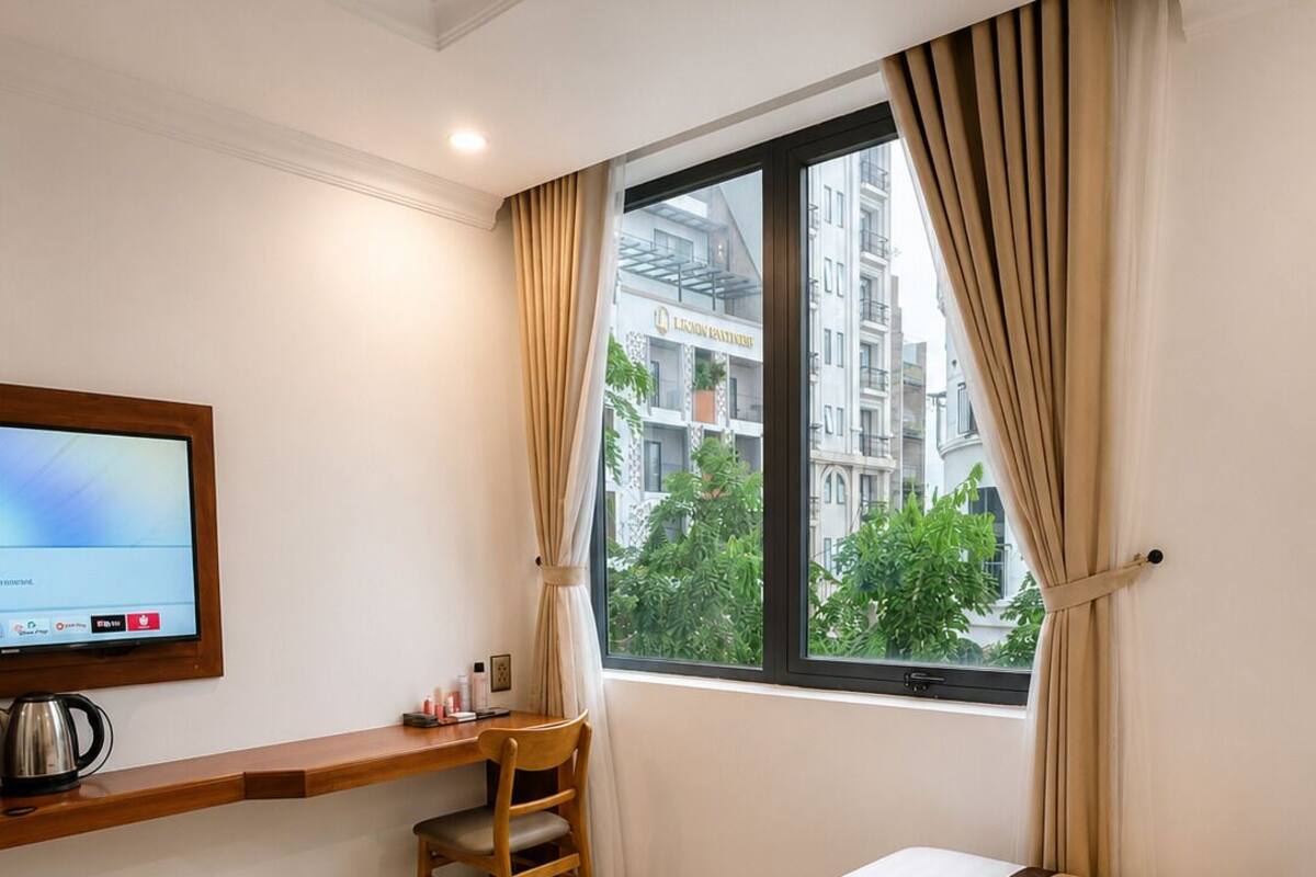 A hotel room with a bed, a desk, a chair, a TV, and a window with curtains.