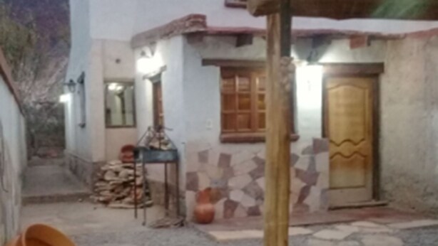 Un edificio rústico con tejado de baldosas, puerta de madera y un pequeño espacio al aire libre con una mesa y sillas.