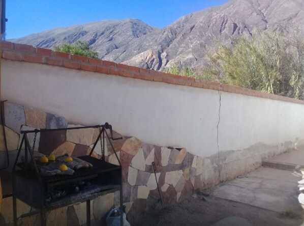 Un barbecue avec des citrons, et un mur de pierres servant de fond, avec une vue sur la montagne.