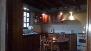 Una cocina con armarios de madera, una estufa y un comedor con mesa y sillas.