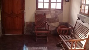 Una habitación con puerta de madera, pared de piedra, ventana con múltiples cristales y un banco de madera.