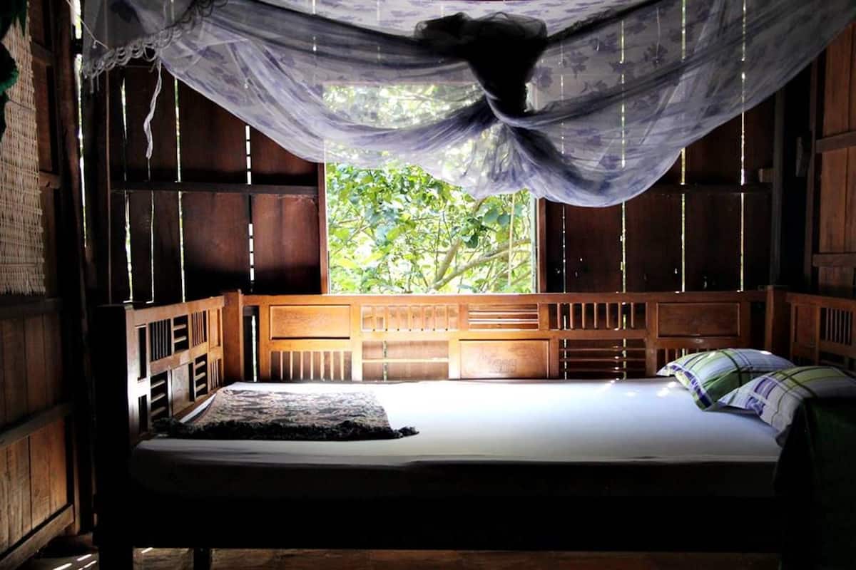Una cama con dosel, cabecera de madera y vistas al exterior.