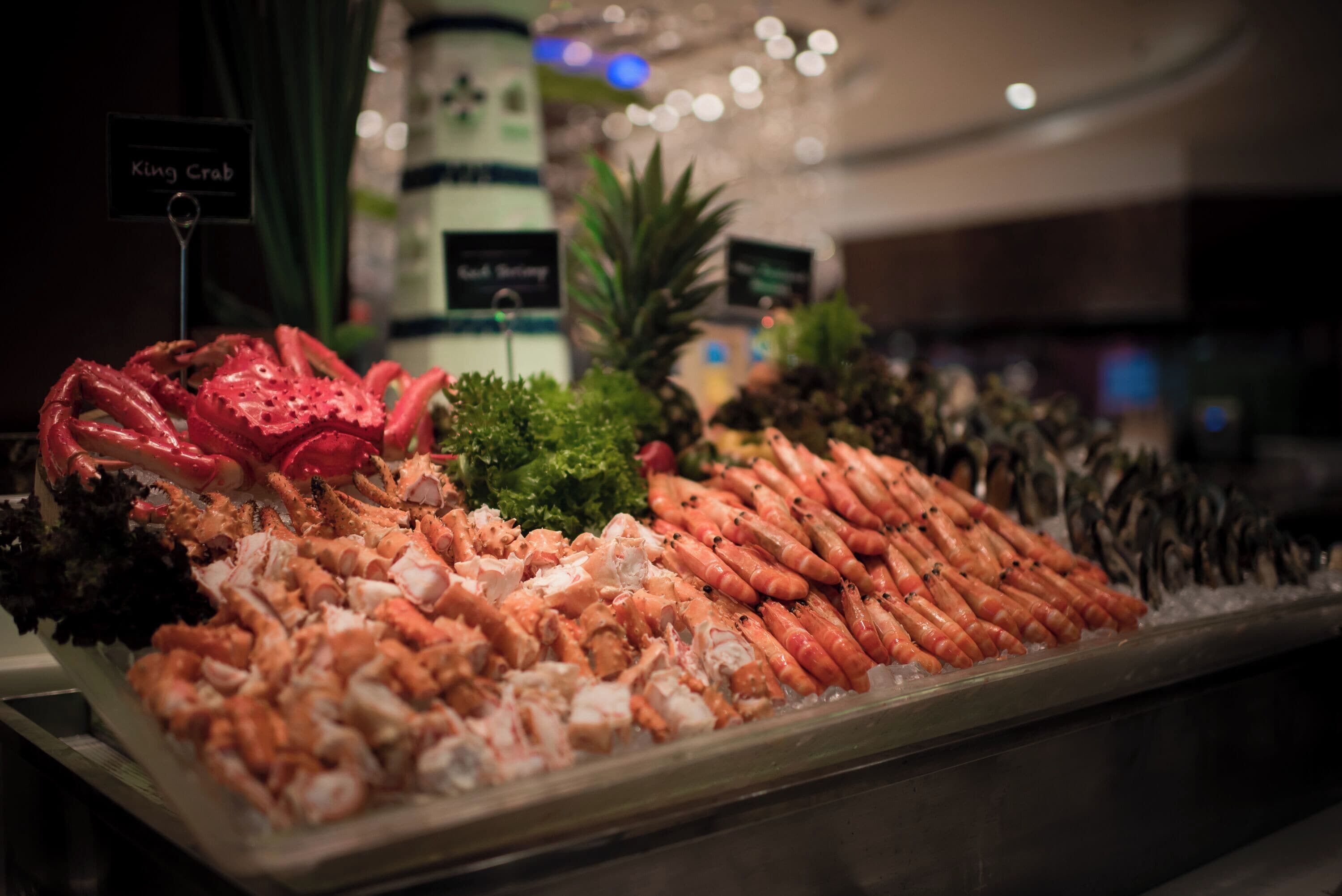 Una exhibición de mariscos con distintos tipos de pescados y mariscos, como camarones y cangrejos, sobre hielo.