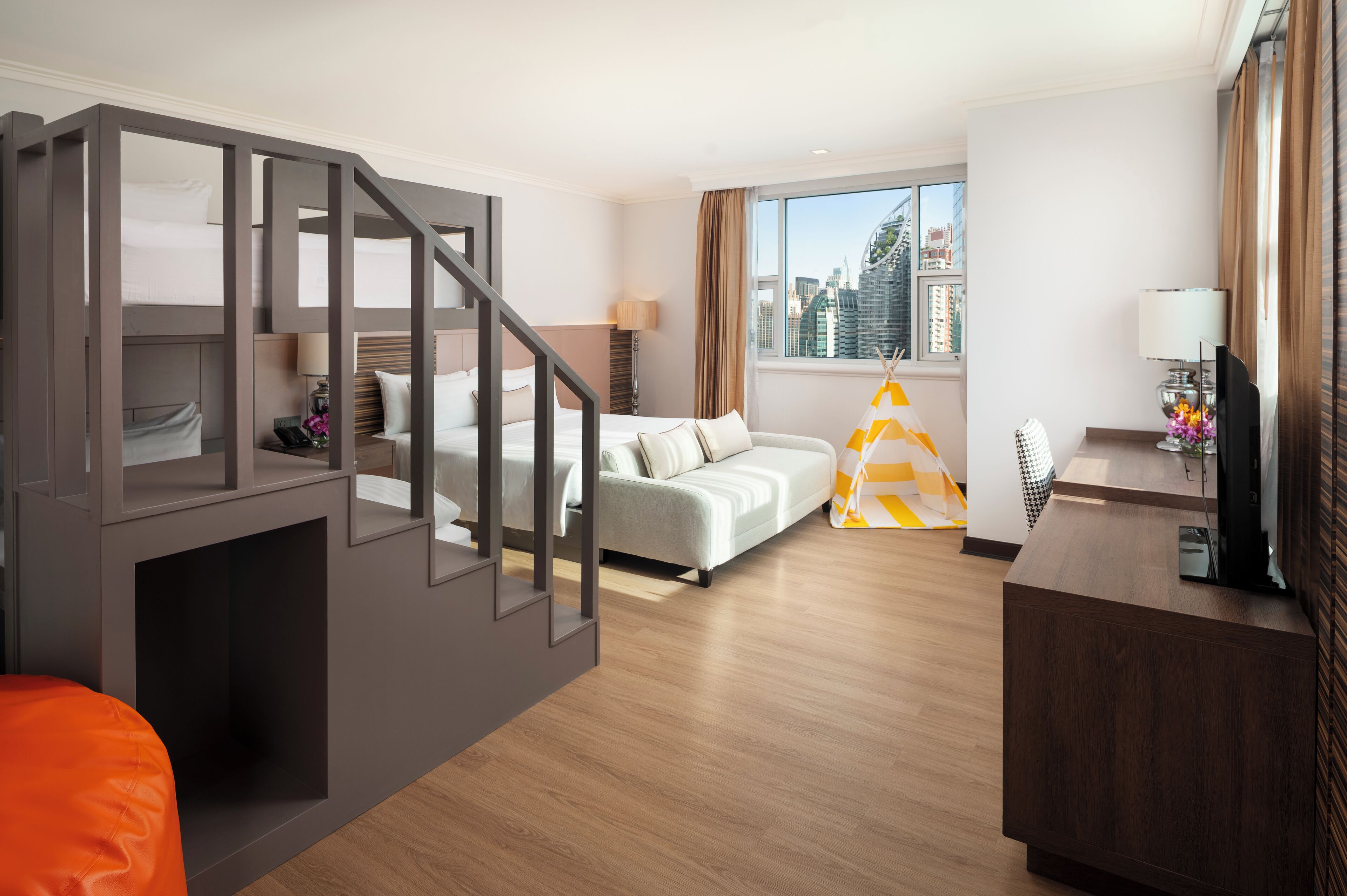 Ein modernes Hotelzimmer mit Treppe, einer Couch, einem Schreibtisch und einem Fenster mit Blick auf die Stadt.