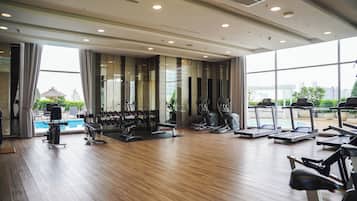 Ein Fitnessraum mit Trainingsgeräten, einem Pool und großen Fenstern mit Blick auf die Stadt.