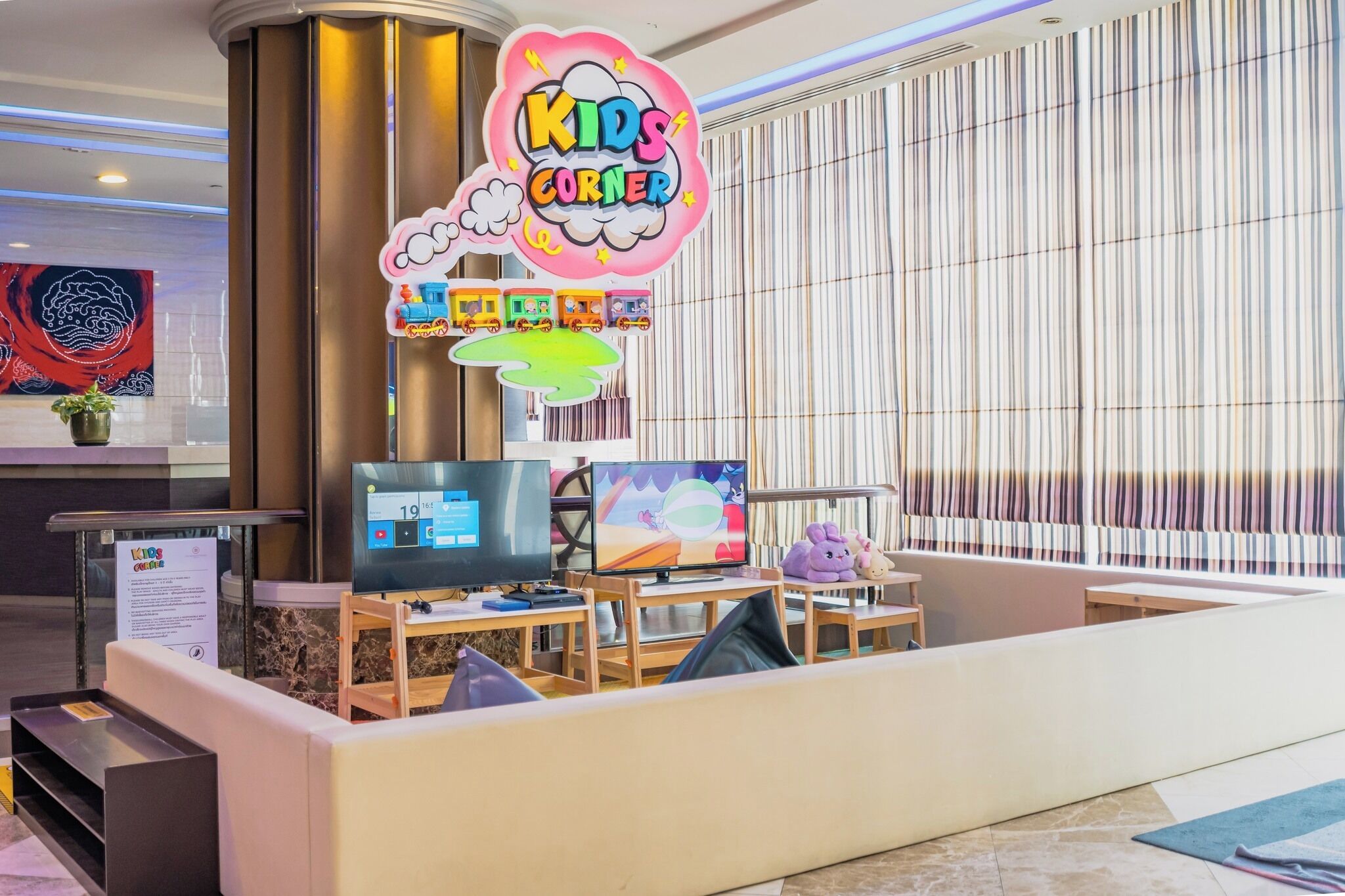 A reception area with a 'Kids Corner' sign, a computer, a television, and a seating area with toys.
