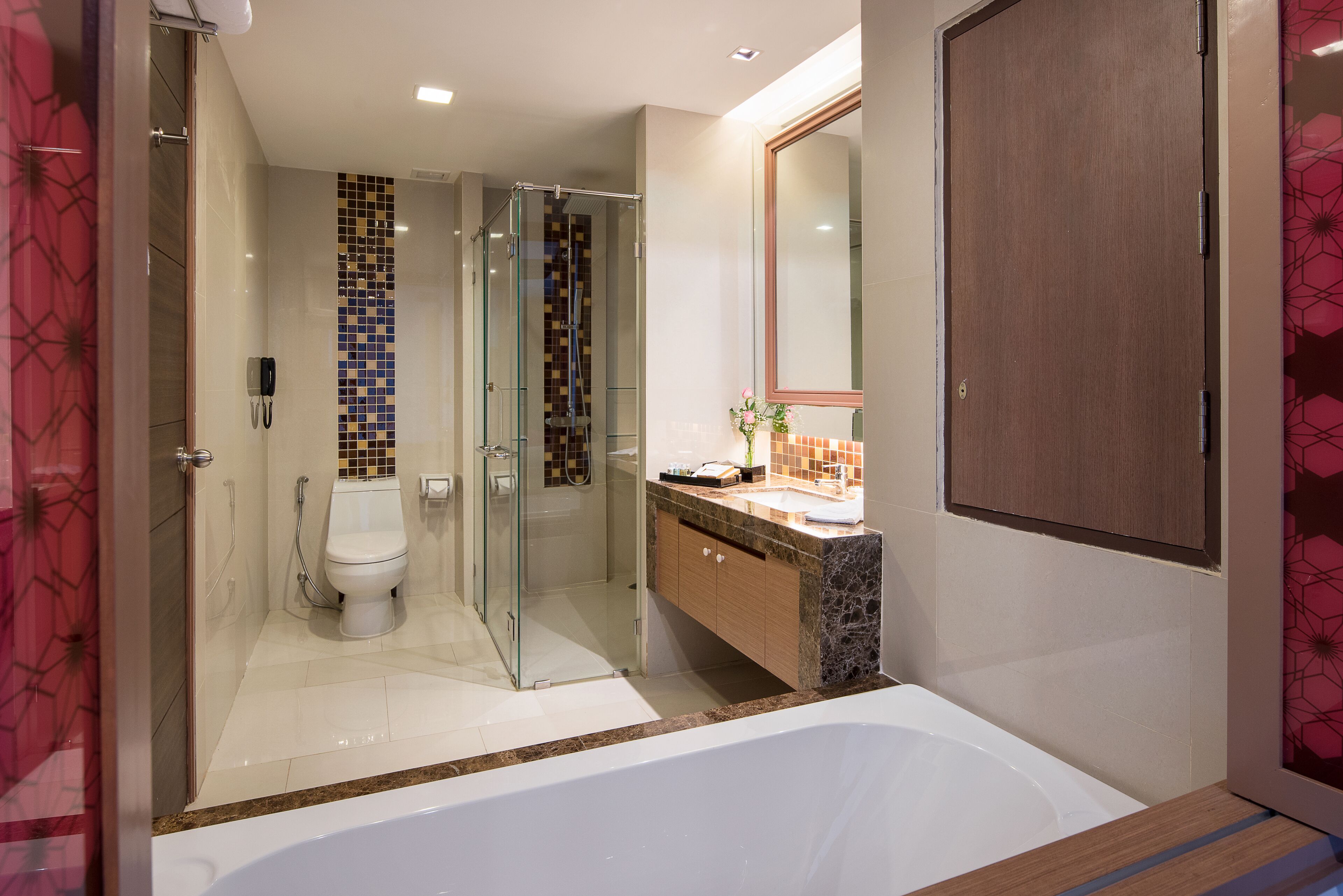 A modern bathroom with a glass-enclosed shower, a white toilet, a marble vanity, and a large mirror.