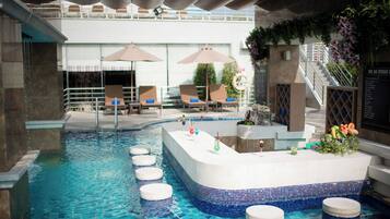 An indoor swimming pool with lounge chairs and a bar area.