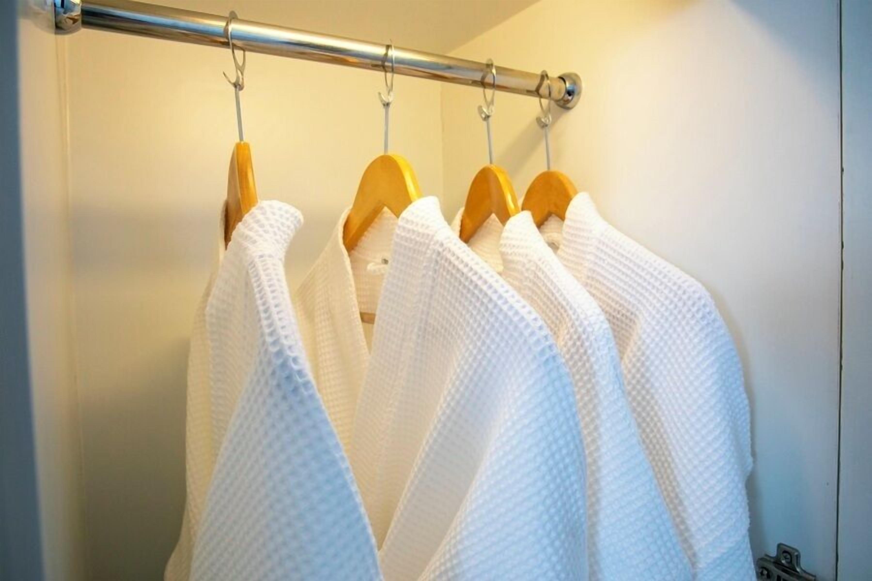 Un portant sur lequel sont suspendues des robes blanches à des cintres en bois.