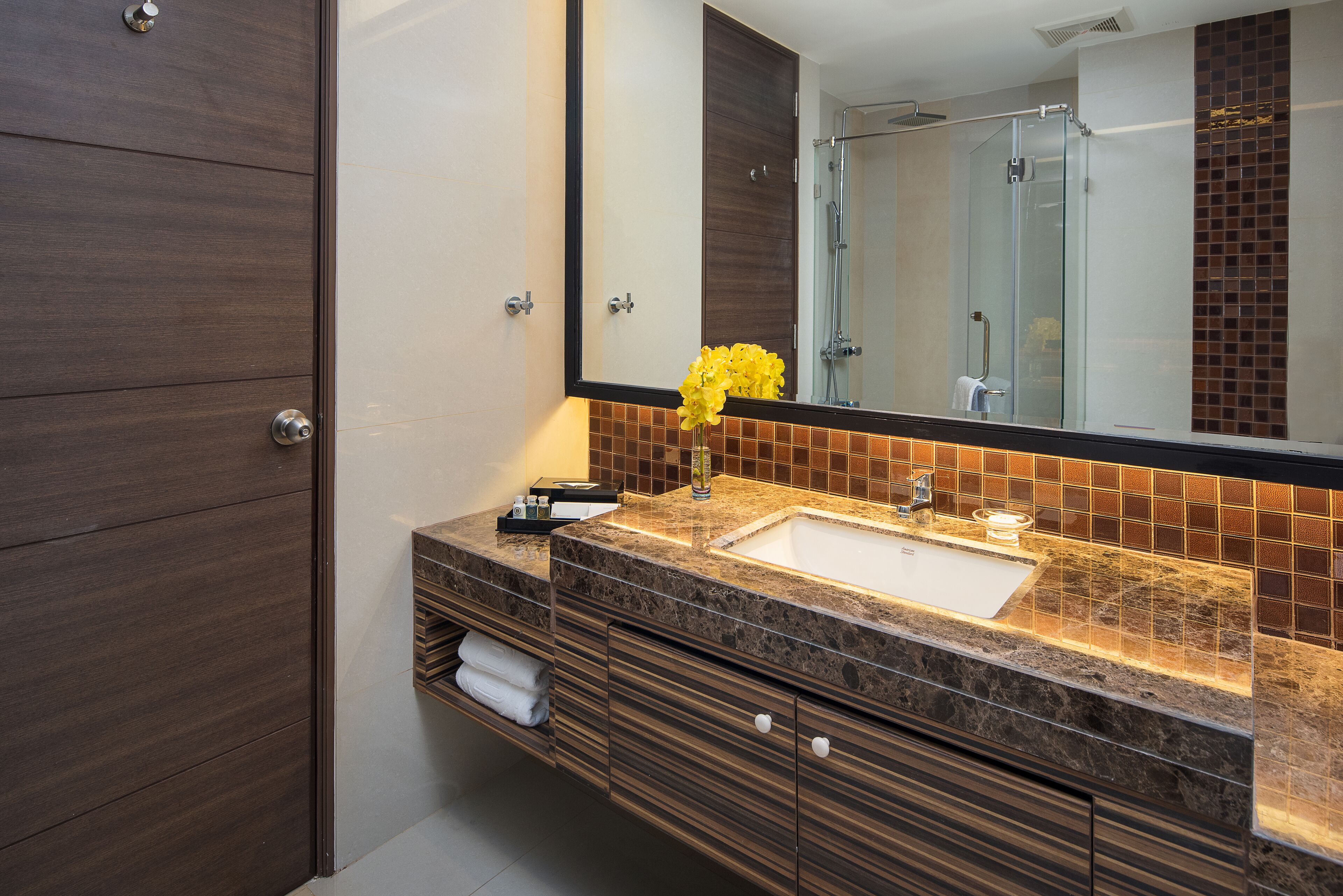 A modern bathroom with a large mirror, a sink, and a shower.