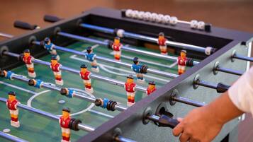 Una mesa de fútbolín con dos equipos, uno rojo y uno azul, y una mano ajustando las barras.