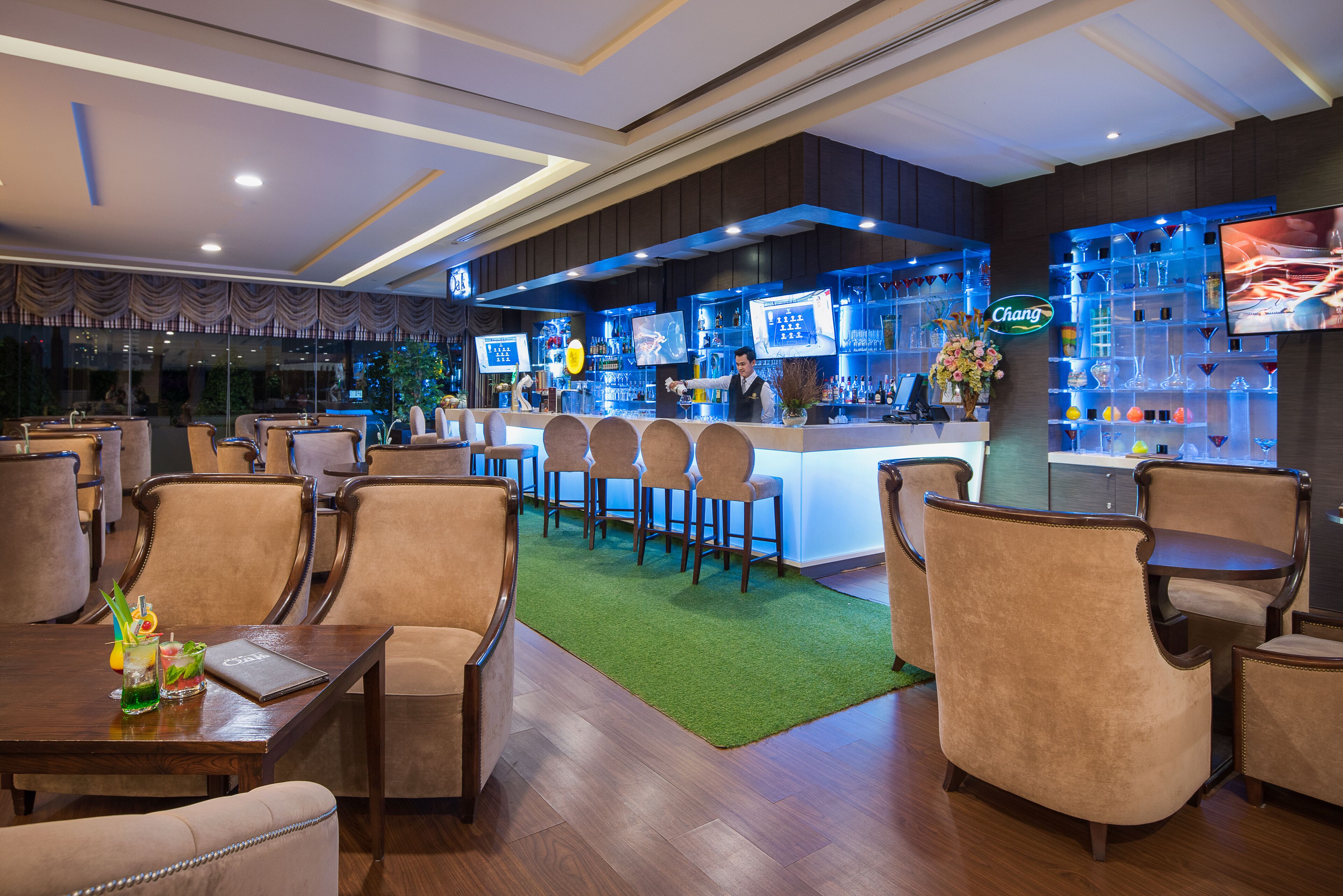 Un área de bar con una barra, taburetes y una pantalla de televisión.