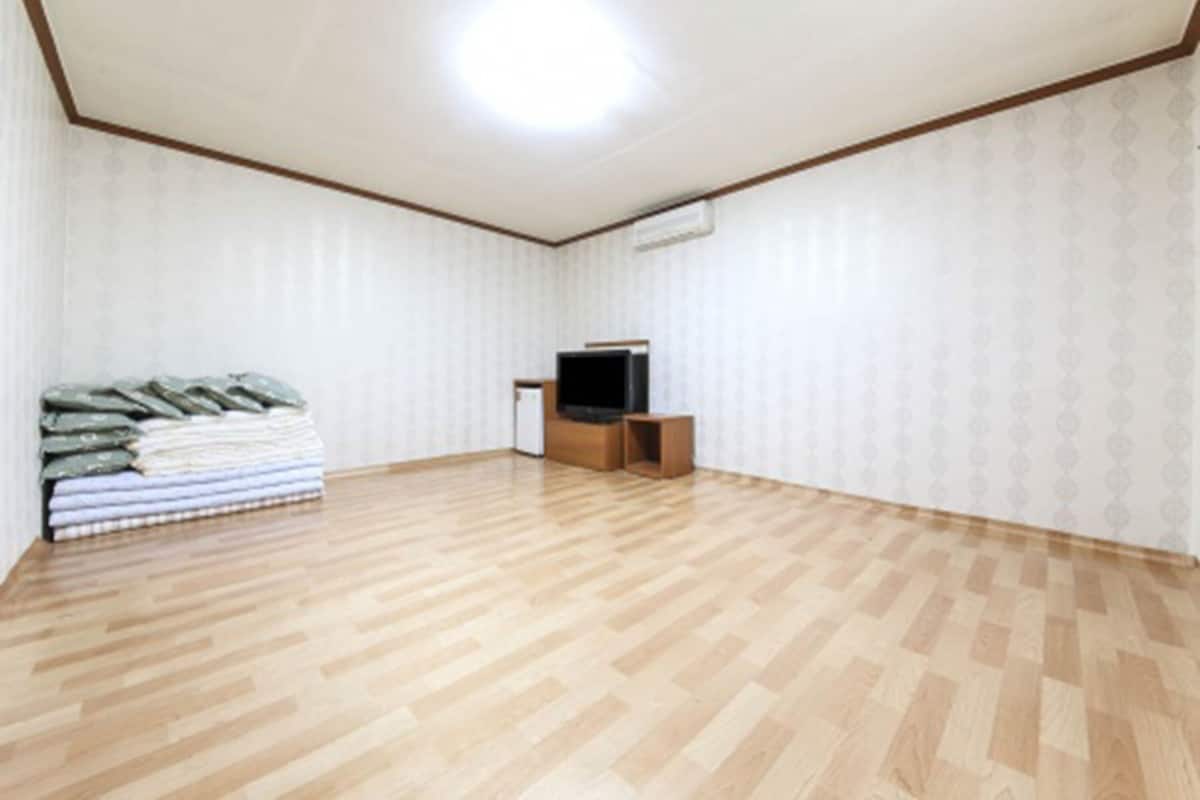 A room with a wooden parquet floor, a television, and a small cabinet.