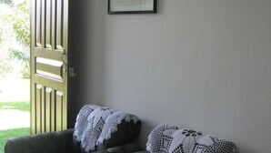 A room with a wooden door, a framed picture on the wall, and a couch with a white blanket. - apartamento completo a 2 minutos ruta 32 (Jiménez)