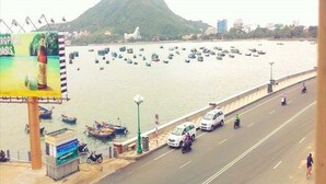A coastal road with boats, a mountain, and a billboard. - My House Hotel Vung Tau (Ho Chi Minh City)