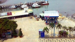 A marina with boats docked, a gas station, and a small building with a sign. - My House Hotel Vung Tau (Ho Chi Minh City)