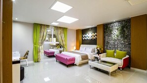 Quarto de hotel moderno com uma cama grande, um sofá, uma mesa de centro e uma parede decorativa.