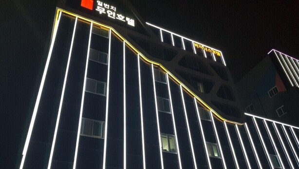 Um edifício com faixas verticais de luz e sinalização em coreano.