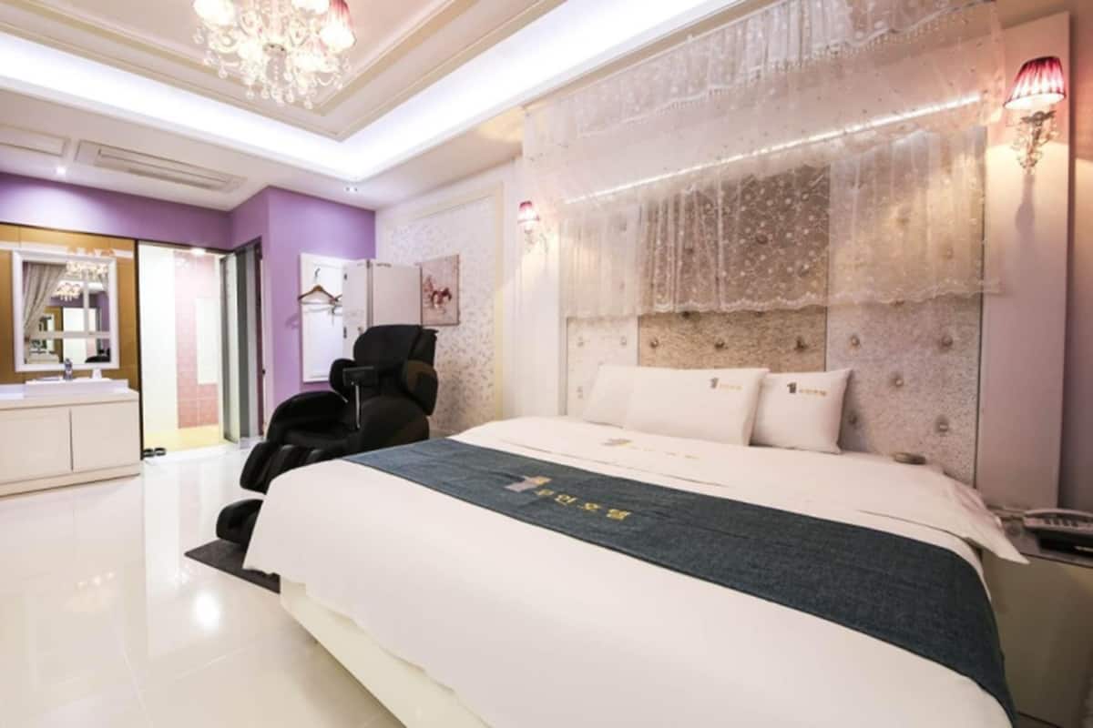 Un dormitorio moderno con una cama grande, una silla y un tocador con espejo.