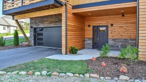 Una casa moderna a due piani con garage, rivestimento in legno e un balcone.