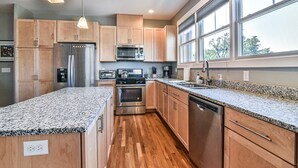 Una cucina moderna con ripiani in granito, elettrodomestici in acciaio inossidabile, mobili in legno e ampie finestre.
