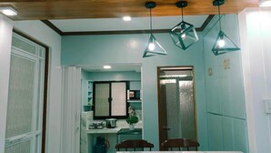 A dining area with a marble table, wooden chairs, and geometric pendant lights. - FABULUZ SIGNATURE STUDIO at Princess Place (Malolos)