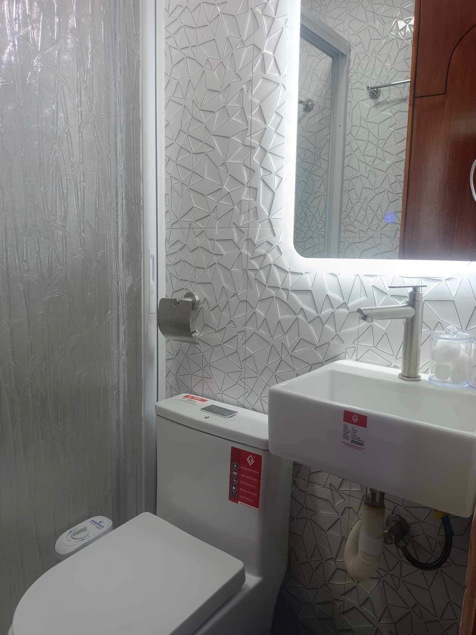 Un baño con inodoro, lavamanos y espejo.