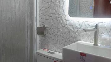 Un baño con inodoro, lavamanos y espejo.