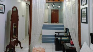 A room with a mirror, a bed with a blue headboard, a wooden chair, and a small table with a red bag. - FABULUZ SIGNATURE STUDIO at Princess Place (Malolos)