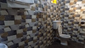 Un baño con pared de azulejos, inodoro, lavabo y ducha.