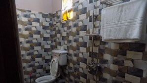 Un baño con inodoro, ducha y paredes con azulejos.